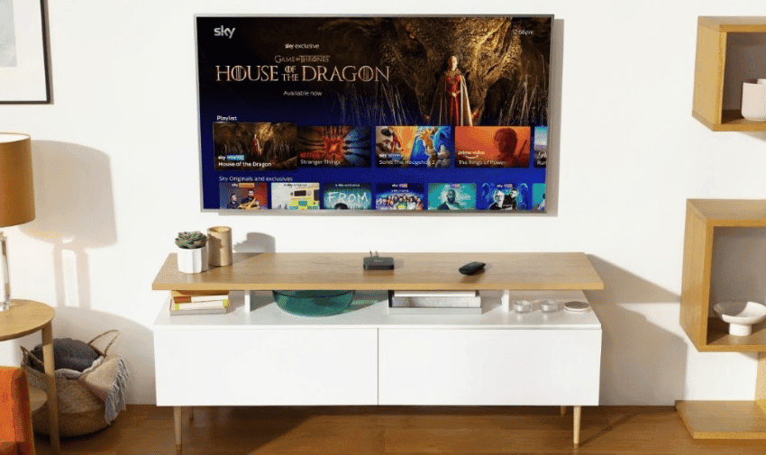 A flat tv is on the wall, the screen shows Sky TV menu with House of Dragons featured at the top. Below the TV is a white cabinet with an oak top.