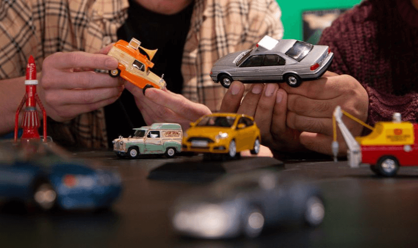 Corgi model toys on a table and being picked up