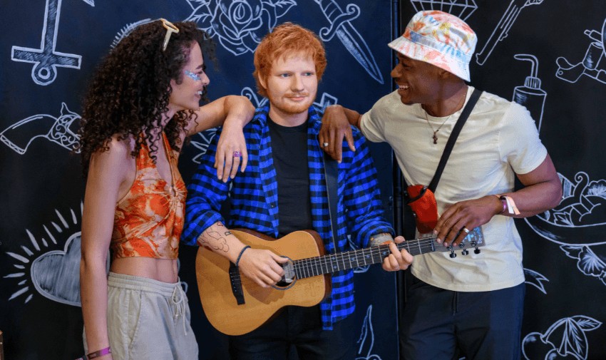 Group of friends taking a picture with a lifelike wax figure of Ed Sheeran at Madame Tussauds, showcasing the interactive and fun experience available at the museum.