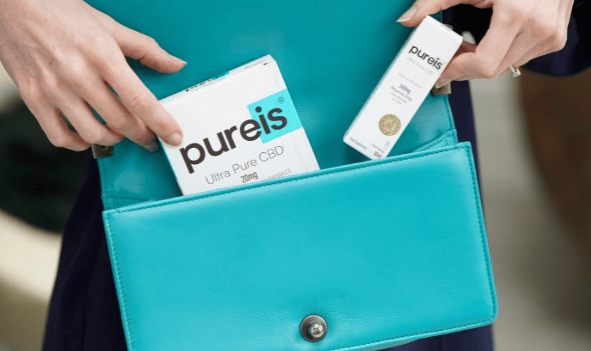 Pureis Ultra Pure CBD products, including capsules and oils, being placed into a vibrant teal handbag. A convenient choice for wellness on the go. Purpl discounts for CBD wellness solutions.