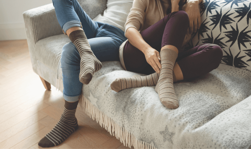 two people snuggling on a sofa - both wearing socks