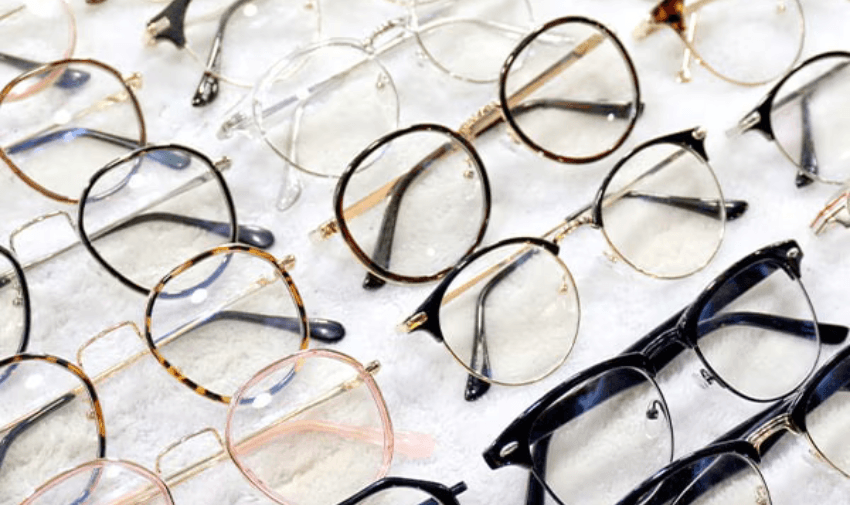 A display of various stylish glasses in different designs and colours, arranged on a white surface. Shopping discounts for disabled people, eye care offers for disabled.