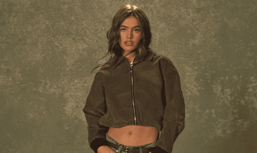 A woman posing in a stylish cropped suede jacket and jeans against a textured backdrop, showcasing Boohoo's trendy fashion. Highlighting Purpl's exclusive disabled discounts for affordable and stylish clothing in the UK.