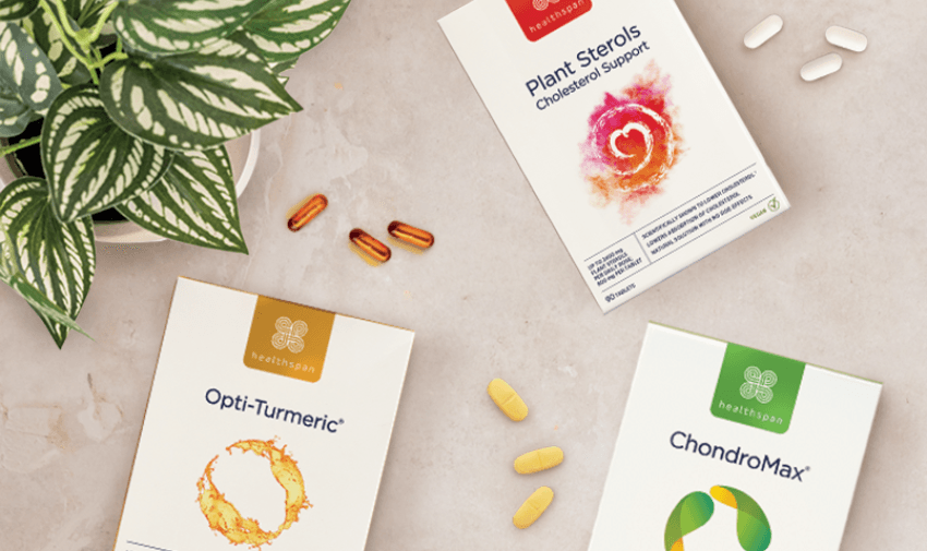 Healthspan supplements image showing three product boxes on a light marble surface. The products include Opti-Turmeric, ChondroMax, and Plant Sterols Cholesterol Support, with various capsules and tablets scattered around, next to a decorative potted plant.