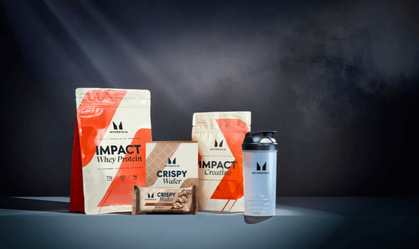 MyProtein products, including Impact Whey Protein, Impact Creatine, Crispy Wafer bars, and a shaker, displayed with dramatic lighting. Great for Fitness Equipment and Disabled Shopping Discounts.