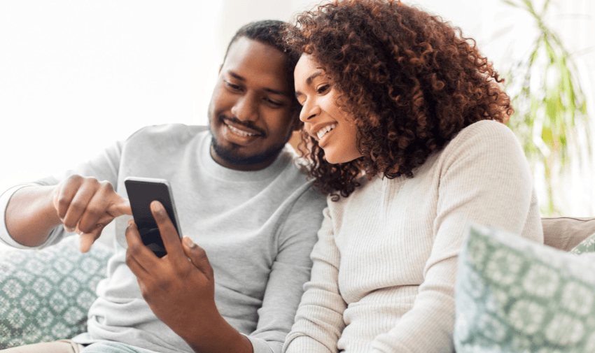 a smiling couple looking at a phone screen, exploring features of the emma app that helps manage finances effectively, offering budgeting and subscription tracking tools, ideal for financial planning for disabled individuals