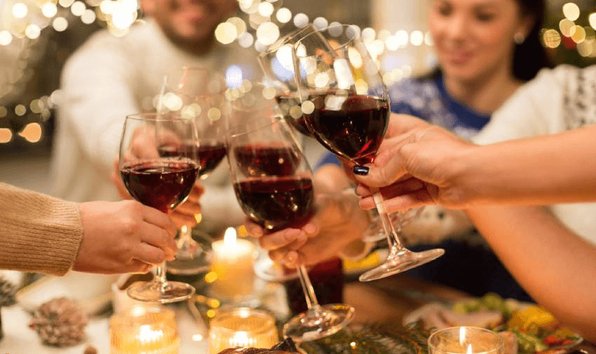 festive wine glasses being clinked in a celebration, surrounded by a cosy atmosphere with warm string lights in the background. perfect for holiday gatherings or special moments. Keywords: wine offers for disabled people, and Christmas gift ideas.