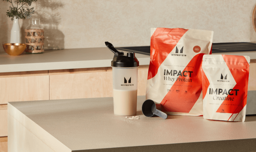 two packs of Impact supplement - Whey Protein and Creatine next to a drinking bottle filled with whey.