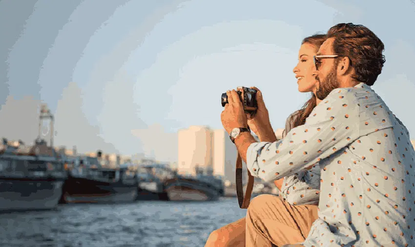 A couple sitting by the waterfront, capturing moments with a camera, representing Radisson's commitment to memorable travel experiences. Highlighting Purpl's exclusive disabled travel discounts, ensuring accessible and luxurious stays for disabled individuals in the UK and abroad.