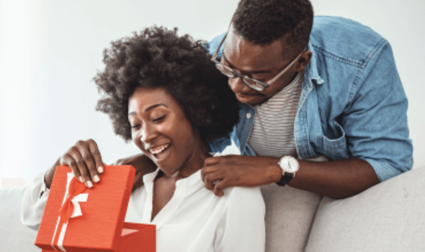 A joyful woman receives a beautifully wrapped gift from a smiling man, creating a heartwarming moment of appreciation and love.