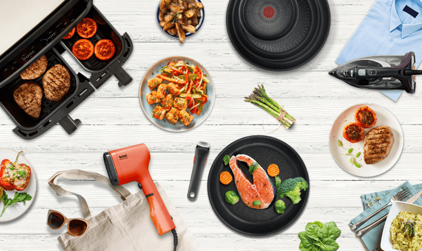 A top-view arrangement of various Tefal products on a white wooden surface: grilled food, an air fryer with steaks and tomatoes, an iron, a hairdryer, a reusable shopping bag, sunglasses, assorted plates of food, asparagus, and a folded blue shirt.