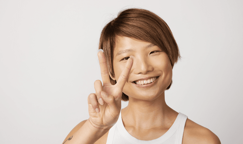 Close-up of a smiling woman flashing a peace sign, highlighting confidence and natural beauty. Perfect for skincare and beauty discounts for disabled people.