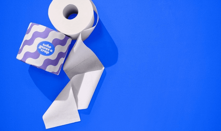 Eco-friendly toilet roll from Who Gives A Crap, unwrapped and partly unrolled, shown on a bright blue background. Great for sustainable home essentials and ethical shopping discounts for disabled people.