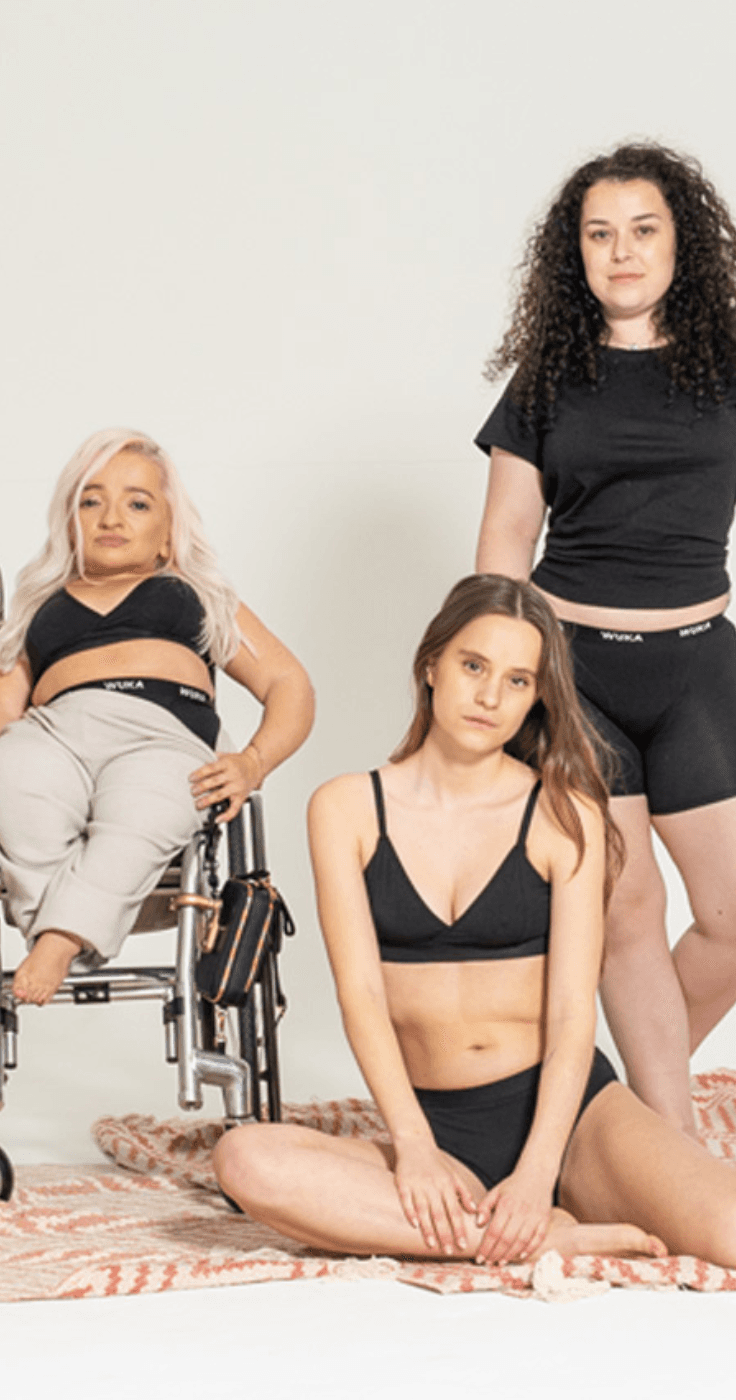 Three women, including one in a wheelchair, wearing WUKA lingerie, celebrating body positivity and inclusivity. Highlighting Purpl's disabled discounts for adaptive and sustainable fashion options in the UK.