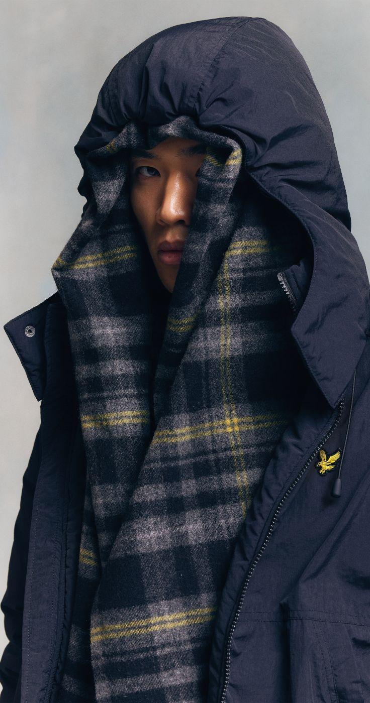 A man wearing a Lyle and Scott navy jacket with the hood up