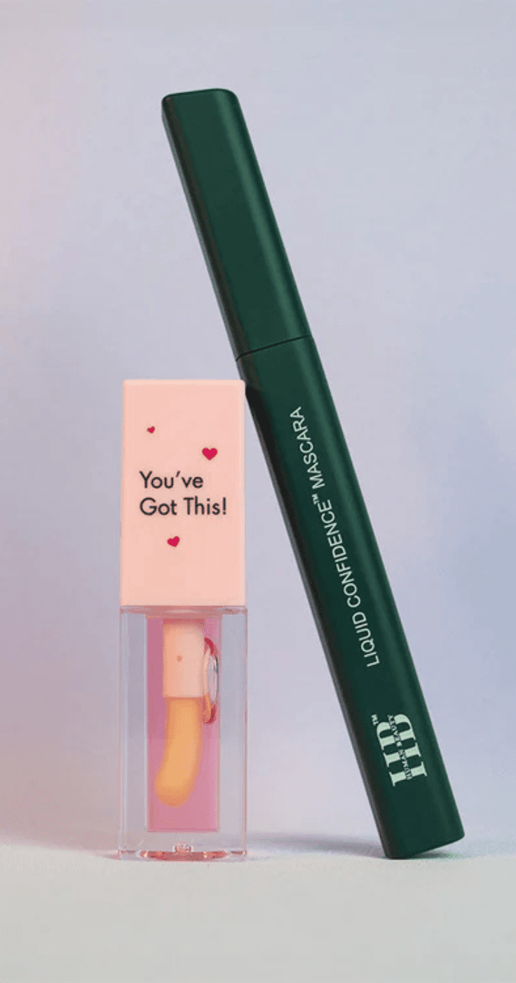 Human Beauty Liquid Confidence mascara and a pink hydrating lip gloss with the message 'You've Got This!' on the cap, displayed against a minimalistic pastel background, promoting self-care and empowerment.