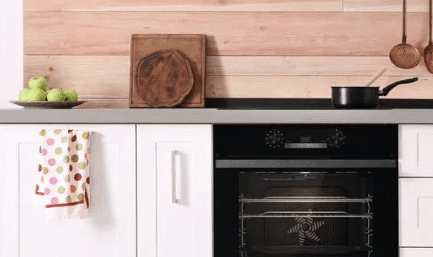 A sleek kitchen setup featuring a built-in oven, a countertop with green apples, and wooden accents. Includes Disabled Discounts and Kitchen Equipment Offers.