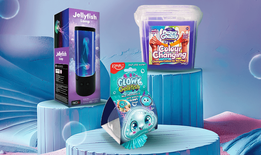 A glowing jellyfish lamp, a container of colour-changing Gozey Gozey slime, and a Glowz gelli fish toy are displayed on geometric pastel blue platforms against a blurred background.