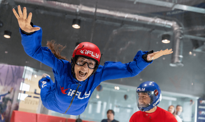 Woman enjoying indoor skydiving at iFLY with instructor support. Accessible skydiving experiences UK, adrenaline adventures for disabled people, inclusive indoor activities.