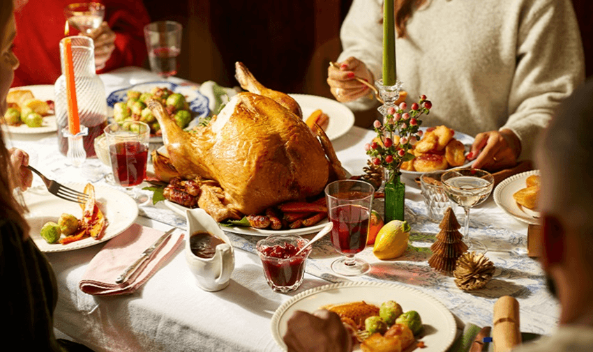 a table set out with Christmas decor and all the trimmings for a Christmas meal including a large turkey.