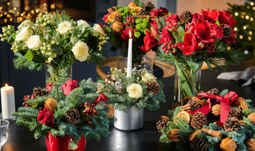 Luxurious Christmas floral centrepieces and wreaths featuring pinecones, red flowers, and green accents.