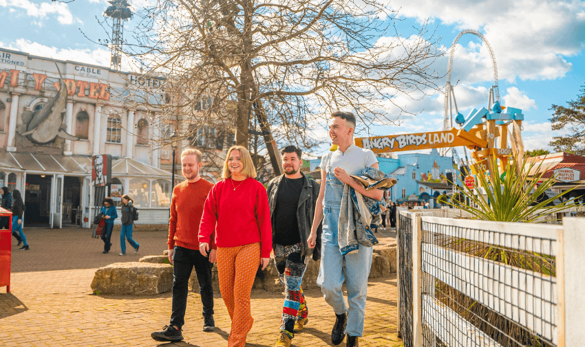 A group of friends walking through Thorpe Park near Angry Birds Land on a sunny day, enjoying the atmosphere. Features Disabled Travel Discounts UK and Leisure Discounts for Disabled Cardholders.