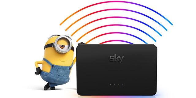 A minion from the Despicable Me film series, wearing denim overalls and goggles, stands next to a black Sky broadband router with colourful wireless signal waves emanating from it. The minion has one hand on the router, appearing pleased.