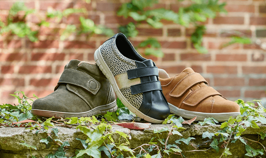 Three pairs of stylish and comfortable Cosyfeet shoes displayed on a stone wall with ivy, showcasing adaptive footwear. Highlighting Purpl's exclusive disabled discounts for wide-fit and supportive shoes in the UK.