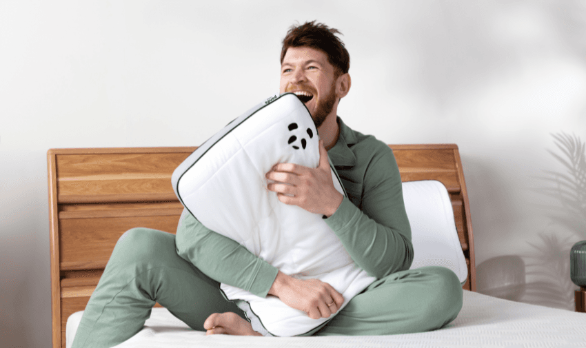 a man clutching a Panda pillow whilst sat on a Panda mattress