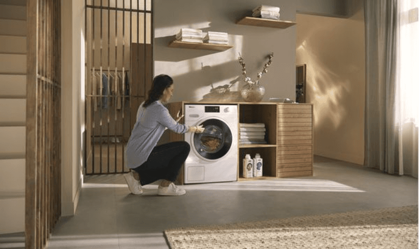 a lady adding laundry to a miele washing machine