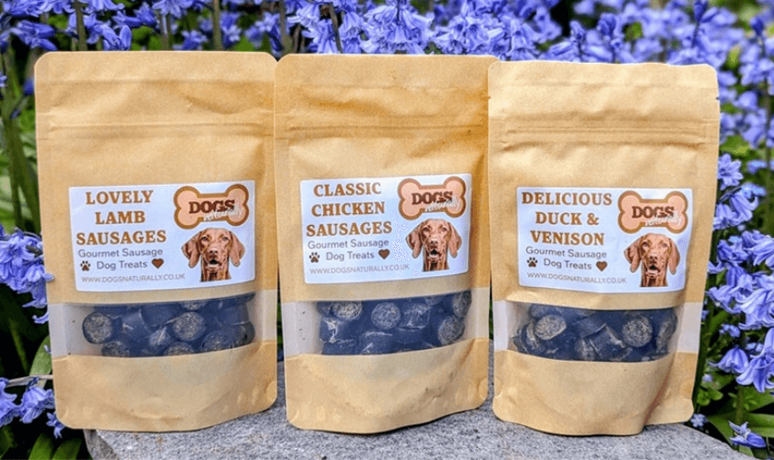 Three packs of Dogs Naturally gourmet dog treats displayed against a floral background, featuring lamb, chicken, duck, and venison options. Ideal for pet owners seeking high-quality, natural dog snacks. Includes SEO for pet care discounts and healthy pet treats.