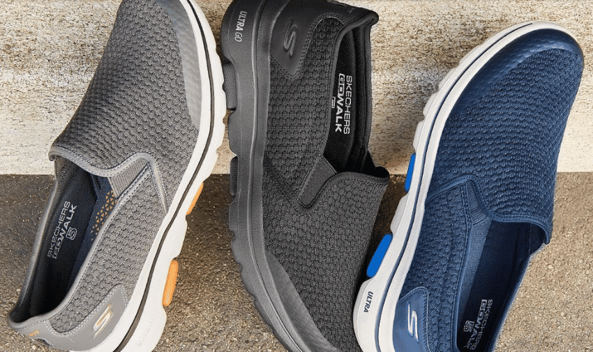 Three Skechers slip-on shoes are showcased. The shoes from left to right are gray with white and orange accents, black with gray and black accents, and navy blue with white and blue accents. They have knitted uppers and branding on the insoles and sides