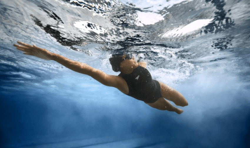 a person swimming and wearing a black Speedo swimsuit