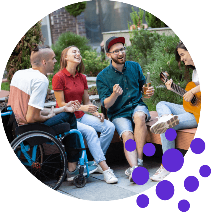 Friends outdoors: 2 women, 2 men, one in wheelchair, enjoying music