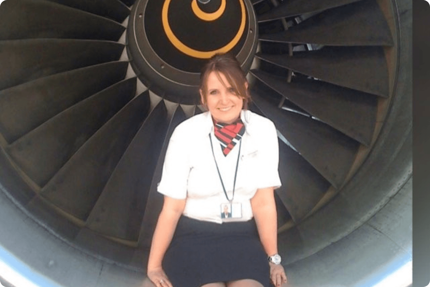 Image of Claire in her air stewardess uniform. She has brown hair tied up and is posing in front of the camera