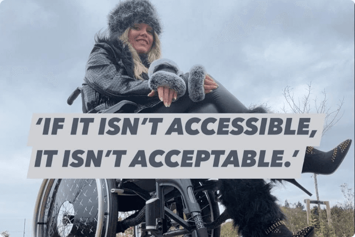 Anoushka is a white woman with blonde hair, she is wearing a coat, gloves and fluffy hat and is sat in a wheelchair against a cloudy sky, there is text across the image that says If it isn't accessible, it isn't acceptable.