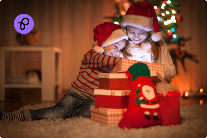 A christmas scene in a living room with two small children excitedly opening a gift