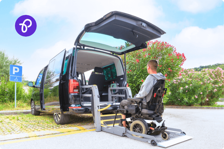 A wheelchair user is entering a mobility car through a ramp into the back of the vehicle