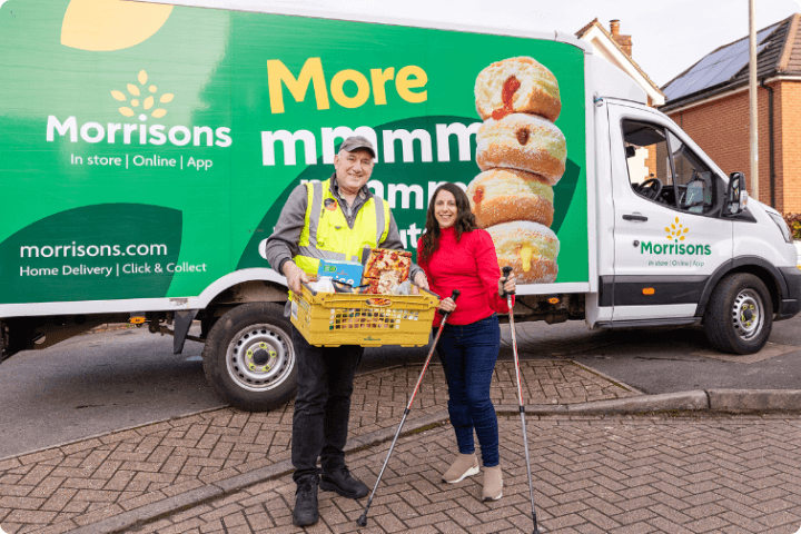 Georgina is a white disabled woman and she stands with a Morrisons delivery driver with her groceries for a post on Purpl Disabled Discount about the Morrisons disabled discount