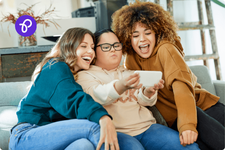 A group of three disabled women are posing for a selfie on a sofa