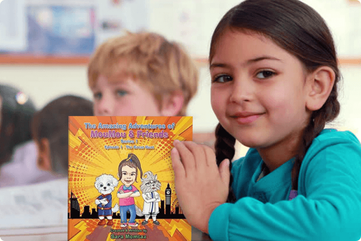 A child is holding a book called MouMou and Friends