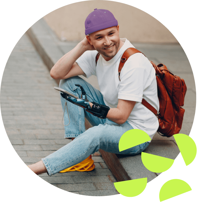 Young man with prosthetic hand using phone on pavement