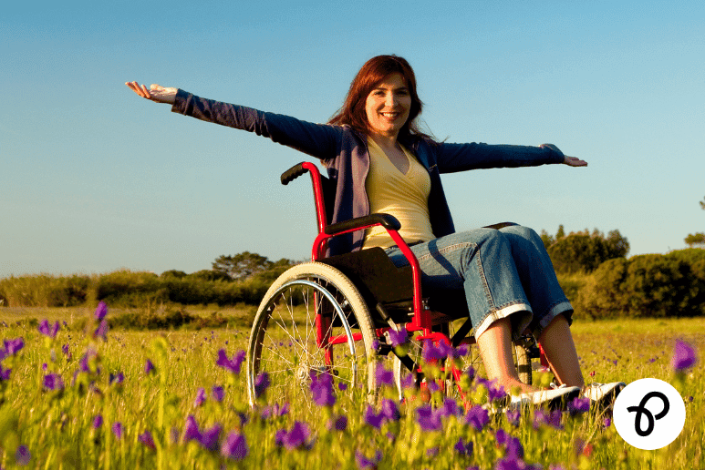 Disabled woman using a wheelchair outdoors with arms outstretched, representing Disability Living Allowance updates for 2026, Scotland cross-border moves, and disability benefits support for people with long-term health conditions in the UK.