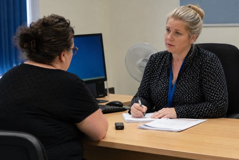 Person attending a face to face DWP health assessment in an office, showing disability benefit assessment support for people with long term health conditions.