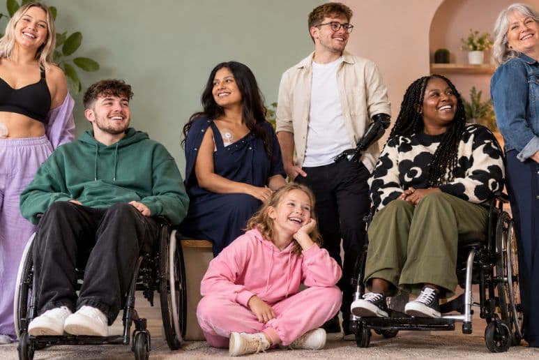 Disabled adults and a child wearing modern adaptive clothing, including wheelchair users and a person with a prosthetic arm.
